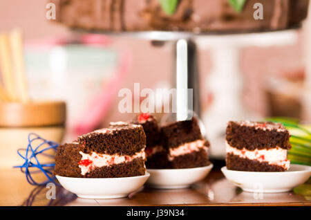 Delicious chocolate cake pieces with cream filling sitting on small plates, pastry concept Stock Photo