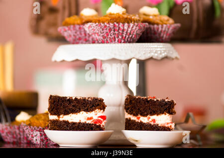 Delicious chocolate cake pieces with cream filling sitting on small plates, pastry concept Stock Photo