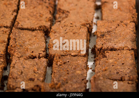 Delicious brown colored chocolate brownies lined up, square pieces as seen from above angle, metal cake cutter being used, pastry concept Stock Photo