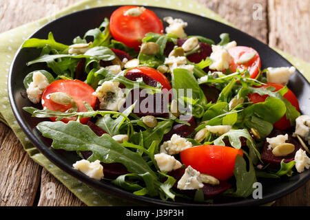 Healthy salad with beetroot, arugula, tomatoes, roquefort cheese and pumpkin seeds close-up on a plate. Horizontal Stock Photo