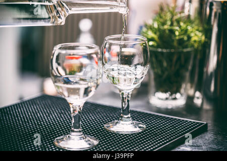 Bartender serving alcohol drinks behind bar counter. Stock Photo