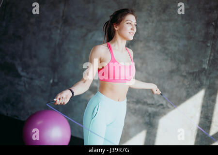 Fitness concept. Healthy lifestyle. Young slim woman jumping with skipping rope in gym Stock Photo