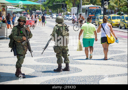 RIO DE JANEIRO - FEBRUARY 10, 2017: Two Brazilian Army soldiers stand in full camouflage uniform on the boardwalk at Copacabana Beach. Stock Photo