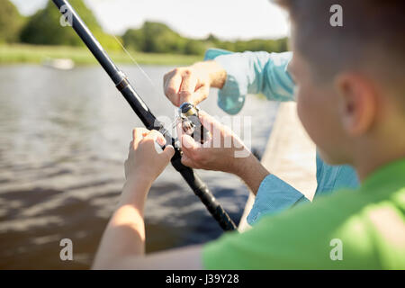 boy and grandfather with fishing rod on river Stock Photo