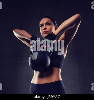 young woman flexing muscles with kettlebell in gym Stock Photo