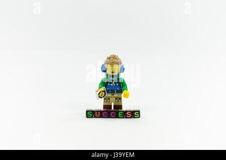 lego hiker miniature standing behind word success spell using colorful alphabet beads. Stock Photo