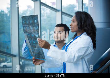 Closeup portrait of intellectual healthcare professionals with white labcoat, looking at full body x-ray radiographic image, ct scan, mri, isolated ho Stock Photo