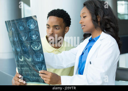 Closeup portrait of intellectual healthcare professionals with white labcoat, looking at full body x-ray radiographic image, ct scan, mri, isolated ho Stock Photo