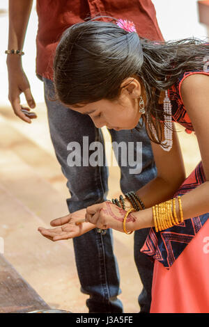 Young girl painting her hand at a traditional Theyyam festival - a colourful ritual dance ceremony in North Malabar, Kerala, South India, South Asia. Stock Photo