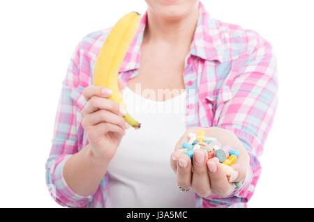 Woman holding banana and tablet pills as alternative nutrients concept on white background Stock Photo