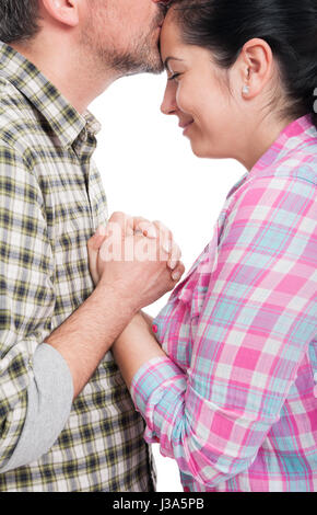 Side view of loving young man kissing woman on forehead isolated on white background Stock Photo