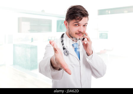 Doctor giving hand for handshake to patient for greetings and recommends while talking on cellphone Stock Photo