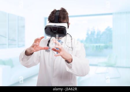 Medical doctor using virtual reality headset at the consulting room and holding something imaginary in hands Stock Photo