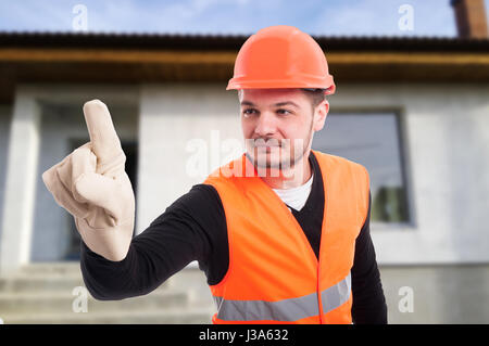Young engineer touching on transparent screen and smiling in front of the house Stock Photo