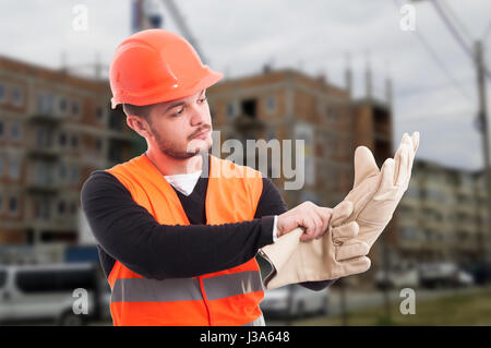 Builder putting protection gloves on hands and getting dressed for work Stock Photo
