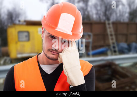 Closeup portrait of attractive builder thinking at something on construction site Stock Photo
