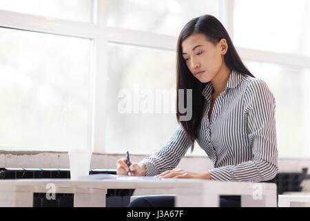 Asian Businesswoman Wrapped up in Work Stock Photo