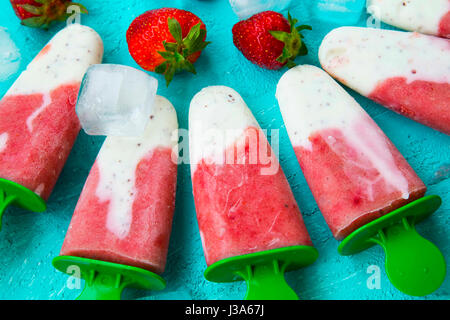 Strawberry and yogurt popsicles with fruits on blue summer background, tasty icy dessert Stock Photo