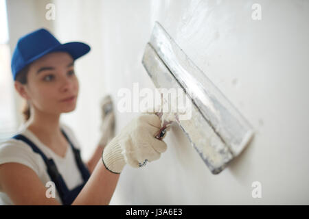 Female Worker Smoothing Out Walls Stock Photo