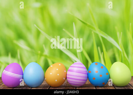 Row of Easter eggs on grass with a wood background Stock Photo