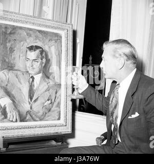 Gary Cooper looking at a portrait of Clark Gable. He is in Paris to play in the film 'Ariane' directed by Billy Wilder. 1957 Stock Photo