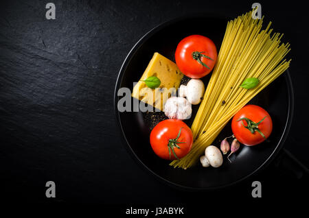 Spaghetti ingredients in black frying pan Stock Photo
