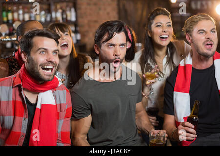 Cheerful friends shouting while looking away in pub Stock Photo