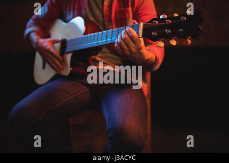 Mid-section of man playing guitar in pub Stock Photo