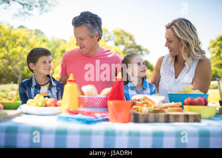 Happy family interacting with each other while having meal in park on a sunny day Stock Photo