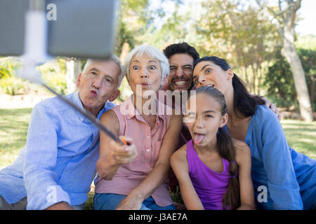 Playful family making funny faces while taking a selfie in the park Stock Photo