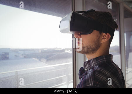 Close up of young businessman wearing vr headset by window in office Stock Photo