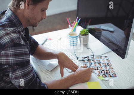 Side view of serious businessman writing in book at creative office desk Stock Photo