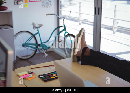 Low section of businessman by laptop and waterpaint on desk in office Stock Photo