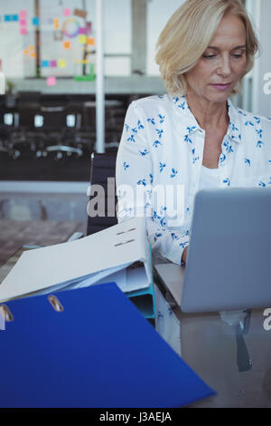 Focused businesswoman working on laptop at desk in office Stock Photo