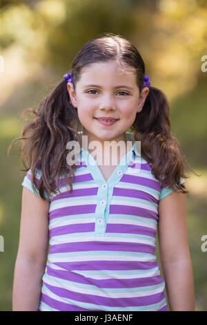 Portrait of smiling little girl standing in forest Stock Photo