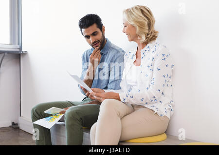 Business colleagues discussing over documents while sitting at creative office Stock Photo