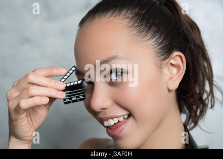 Young pretty woman smiling portrait with movie clapper board near her face Stock Photo