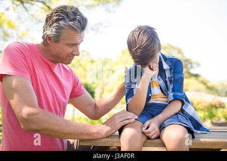 Father consoling his son at picnic in park on a sunny day Stock Photo