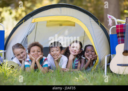 Portrait of smiling friends resting in tent at campsite Stock Photo