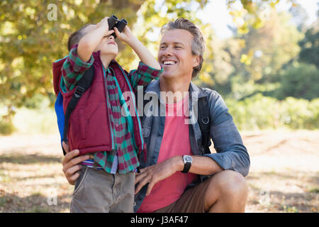 Happy mature father watching at boy looking through binoculars Stock Photo