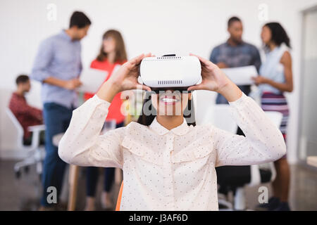 Businesswoman using vr glasses with colleagues in background Stock Photo