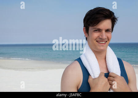 Portrait of smiling man standing on beach with towel around his neck Stock Photo