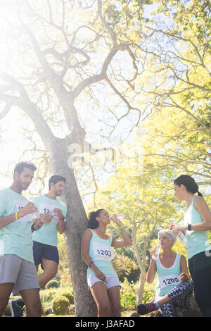 Marathon athletes having water in the park on a sunny day Stock Photo