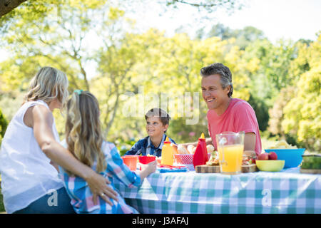 Happy family interacting with each other while having meal in park on a sunny day Stock Photo