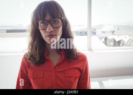 Portrait of serious female designer standing by window in office Stock Photo