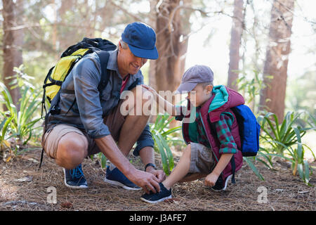 Mature father tying sports shoelace for son in forest Stock Photo