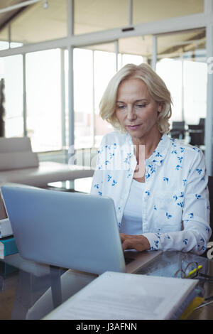 Focused entrepreneur working on laptop at desk in office Stock Photo
