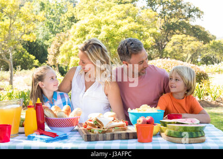 Happy family interacting with each other while having meal in park on a sunny day Stock Photo
