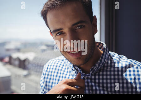 Close up portrait of young businessman by window in office Stock Photo