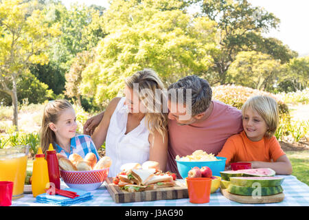 Happy family interacting with each other while having meal in park on a sunny day Stock Photo